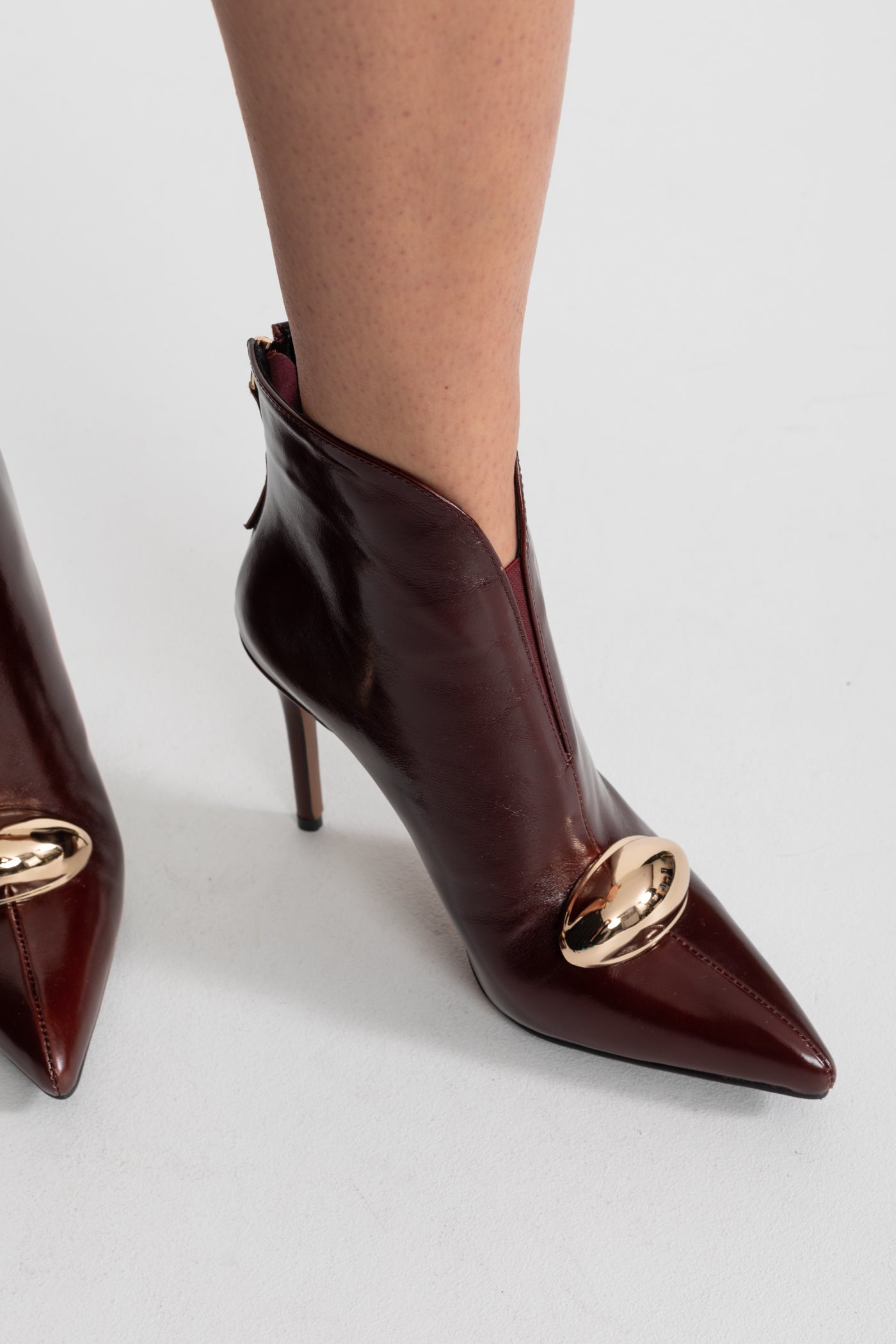 Leder-Stiefeletten mit spitz zulaufender Zehenpartie und goldener Schnallendetail – Burgunderrot